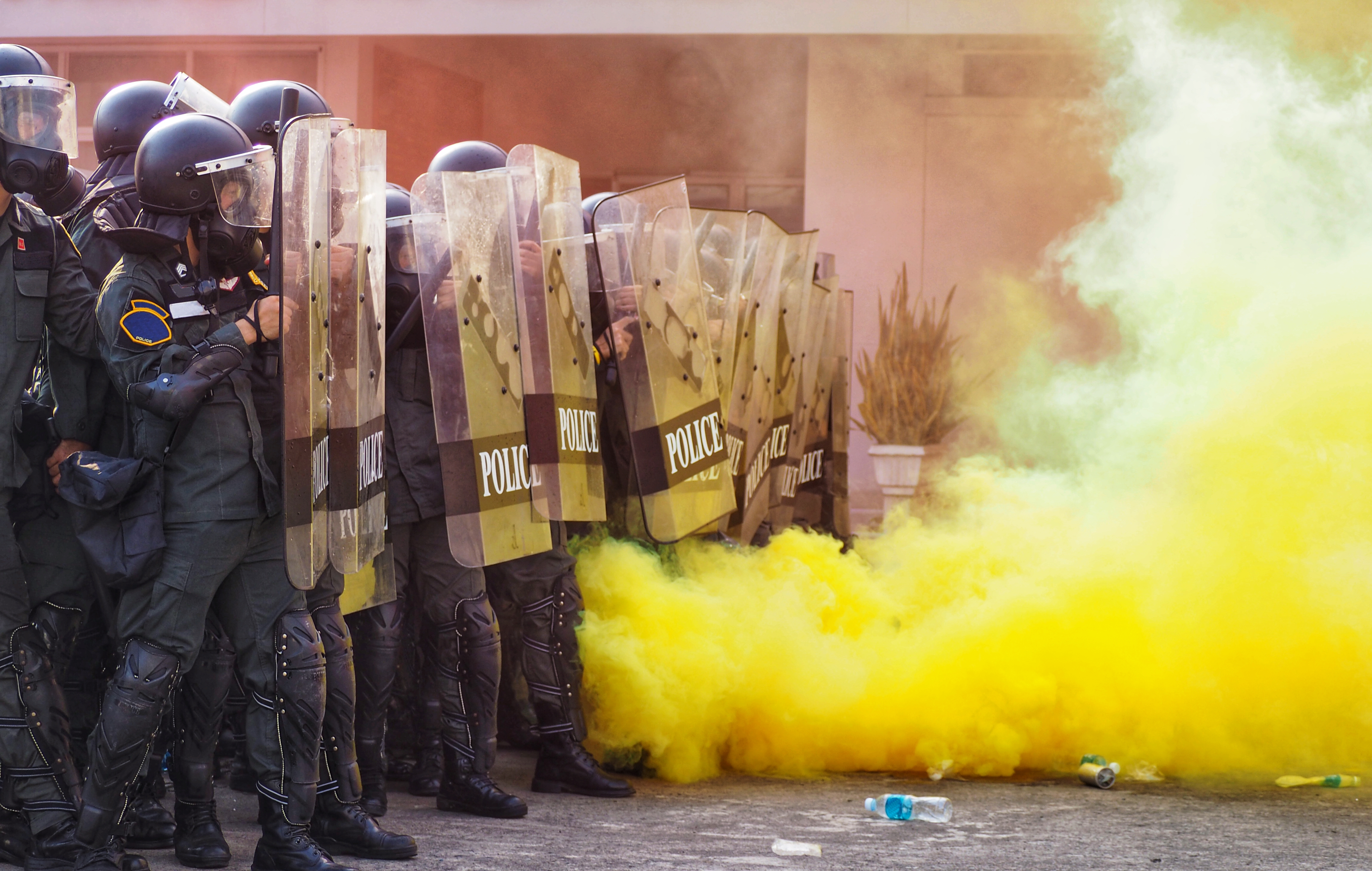 riot police pushing back in front of yellow smoke