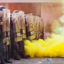 riot police pushing back in front of yellow smoke